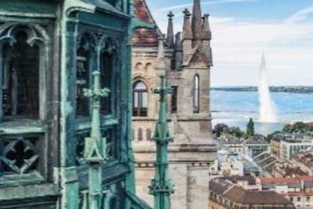 Close up of Geneva church building with more swiss buildings and the lake in the background