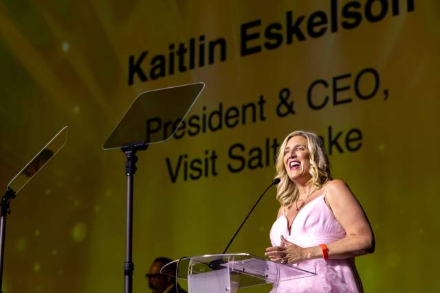 Kaitlin Eskelson wearing a formal pink gown smiling while talking at the podium for the 2025 Salt Awards