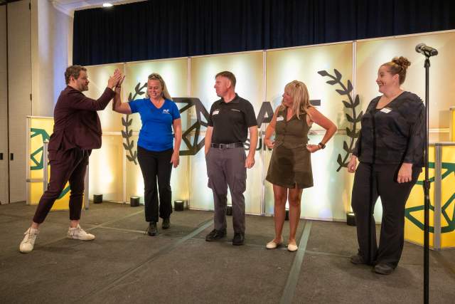 People standing on stage and interacting with the host. The backdrop has the Salt Summit Logo