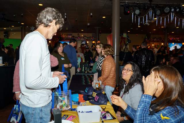 Man standing in front of a registration table taling to the women who are sitting behind it