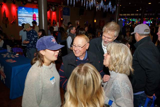 Group of people chatting together. Background shows a bar and other people also networking