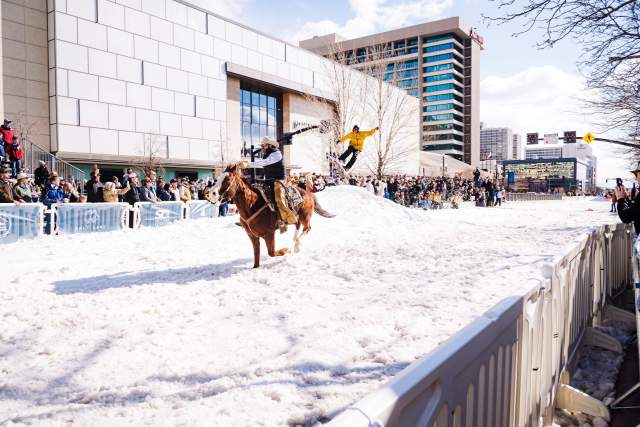 In this photo, a man is riding a horse dragging a skier off a mound on West Temple in Downtown Salt Lake. The road is covered in snow and the photo is from a 2024 event in February called Winter Roundup.