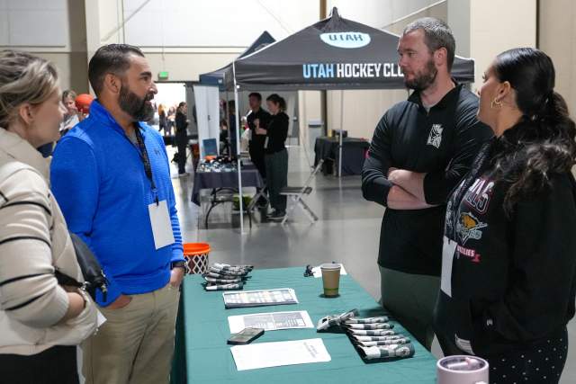 A man and a woman talking to a man and a woman at a vendor table