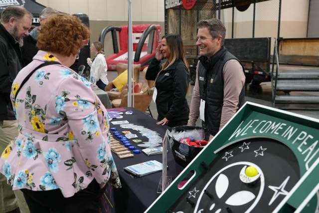 Woman looking at items on a vendor table at the 2024 Sports Summit