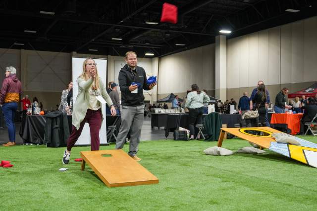 People playing cornholl on a fake grass field
