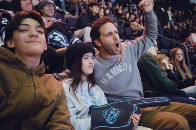 Family sitting in stadium seats wearing Utah Mammoth gear and cheering