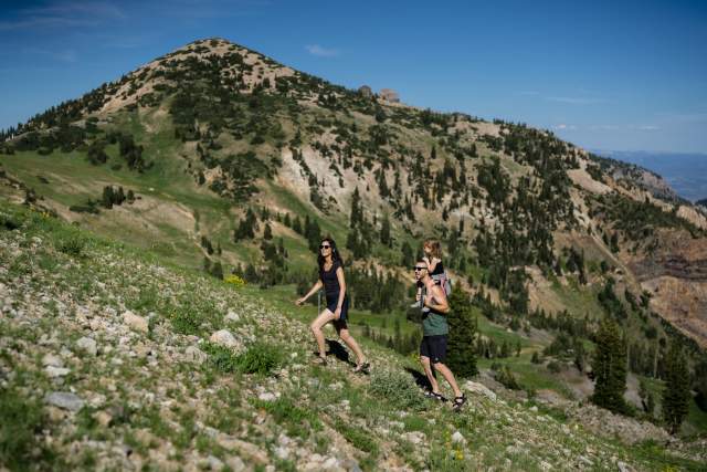 Familiy Hiking up a hillside with a mountain and blue skies in the background