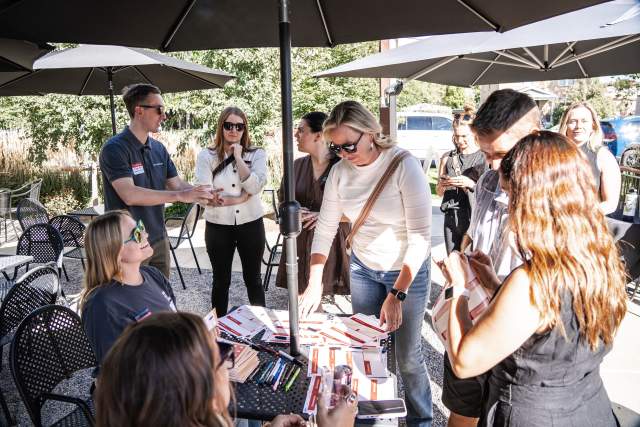 Group of people around a table collecting or turning in bingo stamped cards