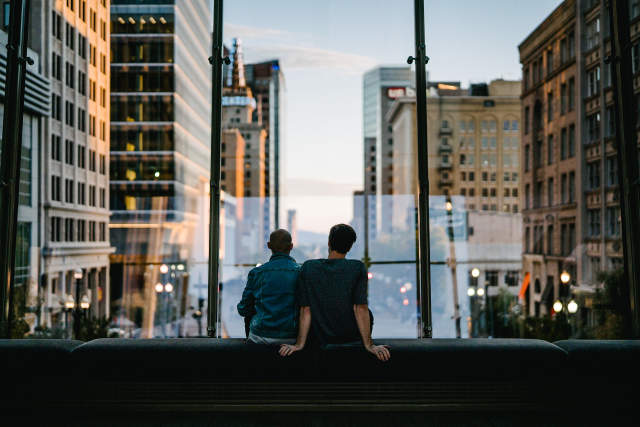 Two people sitting on a bench in the walkway at City Creek over main street looking down Main street