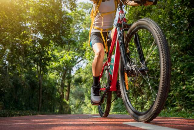 A close up of a cyclist on a red bike traveling down a path