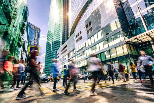 People crossing the street, surrounded by skyscrapers.