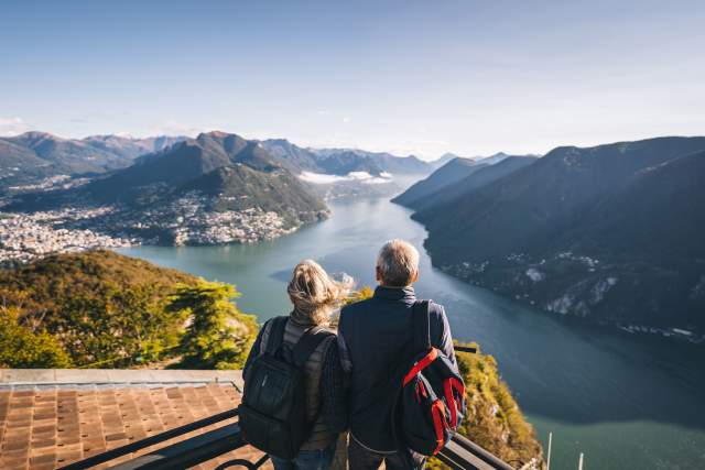 Mature couple relaxing after a hike above lake Lugano in the morning