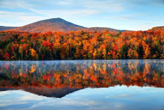Early morning autumn light near Killington, Vermont. Colorful fall foliage reflecting on a lake.