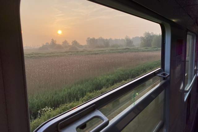 Open train window looking over European countryside