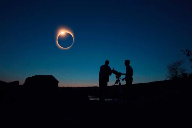 Two men set up a telescope to watch an eclipse