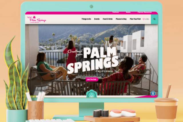 A teal colored desktop monitor mocked up with the Palm Springs website on it.