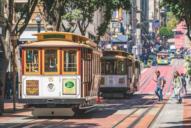 Powell and Market cable car going up a hill in sunny San Francisco.