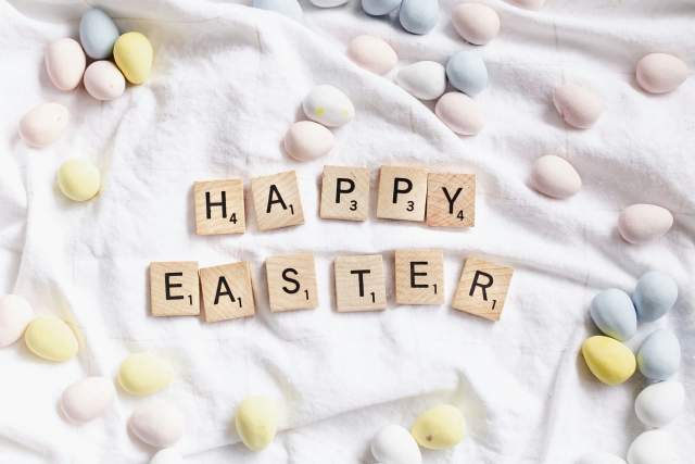 Wooden tiles spell out "Happy Easter," with dyed easter eggs surrounding them.