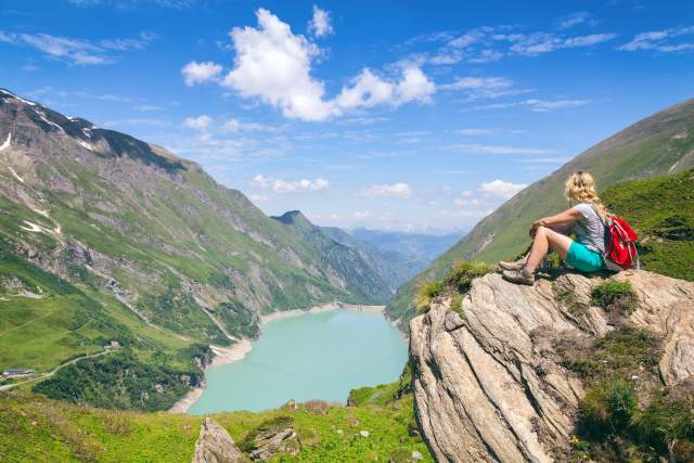 A hiker overlooks a pristine mountain lake, reflecting the regenerative tourism focus on restoring and protecting natural landscapes.