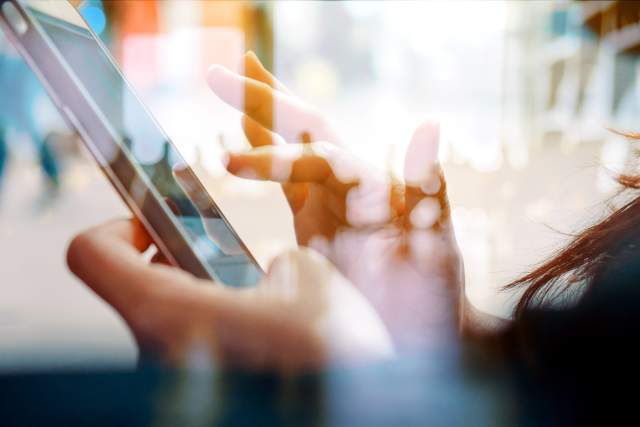 Hands using a smartphone in a public setting, representing digital accessibility and inclusion.