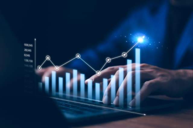 Hands typing on a laptop with glowing bar and line graphs representing data analytics.
