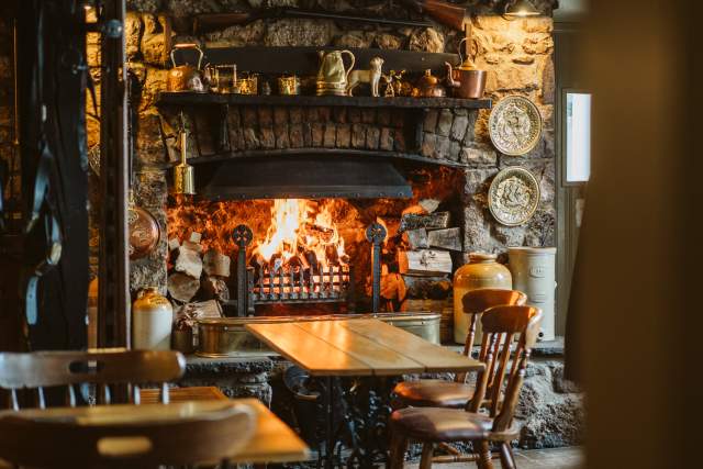Fireplace lit and empty tables at King Arthur Hotel and Restaurant