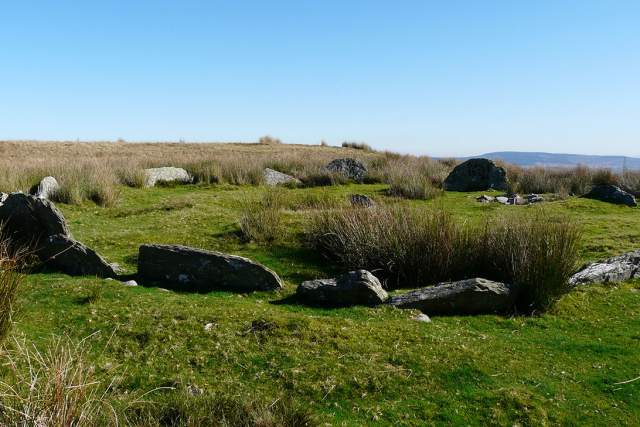 Flat stones around 40cm high buried in a circle formation in a rural setting.