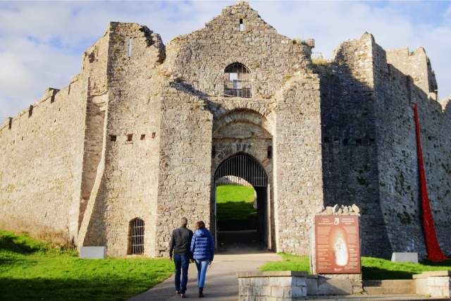 Two people walking into Oystermouth Castle.