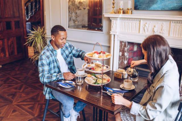 A man and woman enjoying a table full of afternoon tea at Parc le Breos