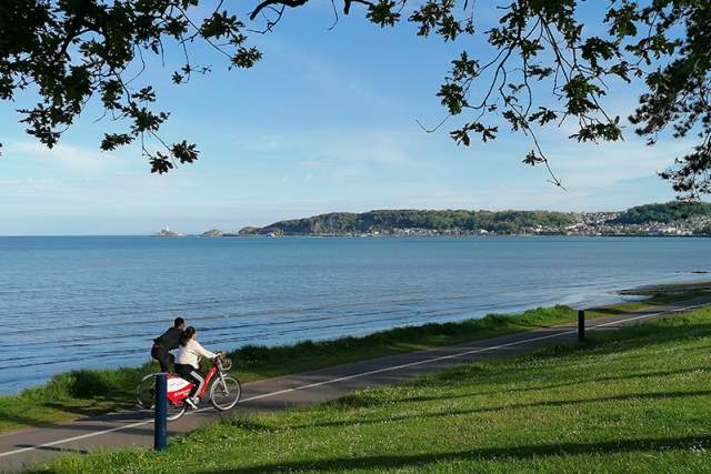 Cyclists on Swansea Prom with the sea in the background.