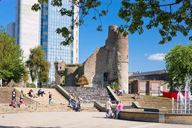 photo of swansea castle with pedestrians walking past in the foreground