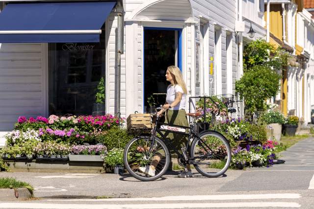 Kvinne på sykkel foran Annemones blomster i Posebyen