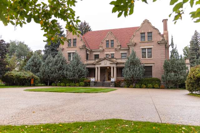 The Trail End mansion in Sheridan, Wyoming, surrounded by trees and manicured lawns on a cloudy fall day.