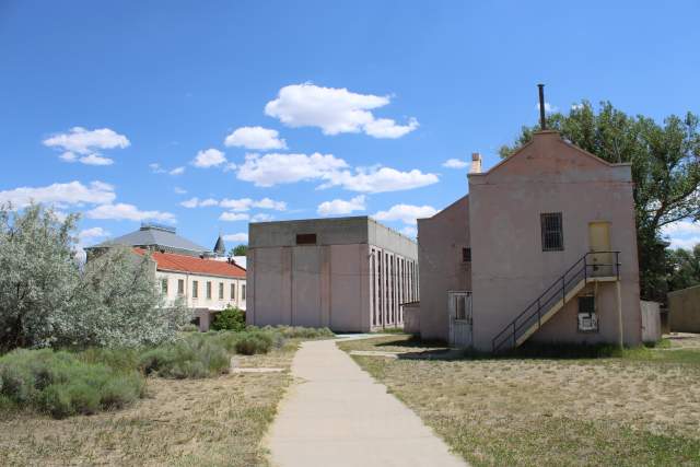 Pink stucco prison outbuilding with barred windows and an exterior staircase, part of the Wyoming Frontier Prison complex.