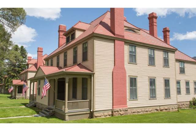 Two historic buildings surrounded by grass lawns and trees at Fort Yellowstone.