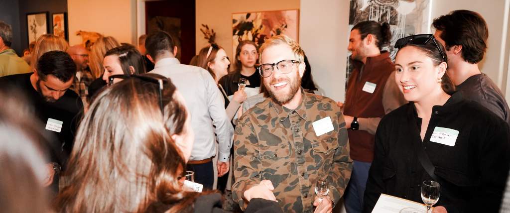 Smiling people with nametags on shaking hands and talking