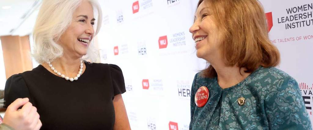 Two women speaking together, background says U Women Leadership Institute
