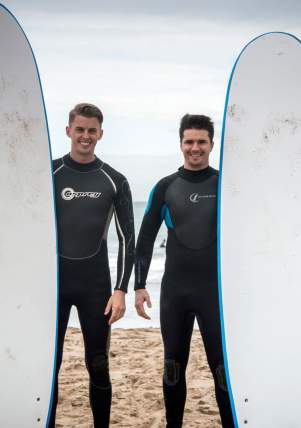 Two surfers pose with their boards in front of the sea Whiterocks Beach, Portrush, County Antri