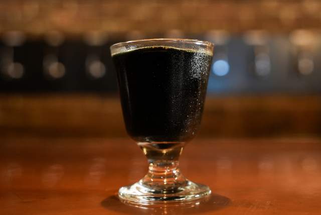 A glass with dark liquid on a bar