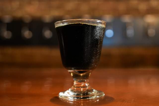 A glass with dark liquid on a bar