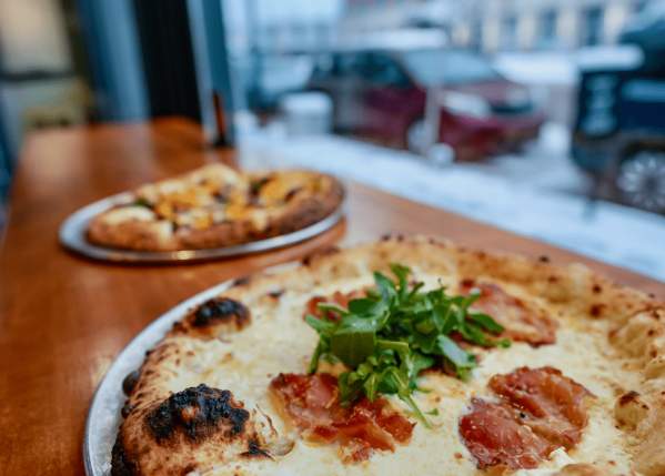 Two pizzas on a table by the window
