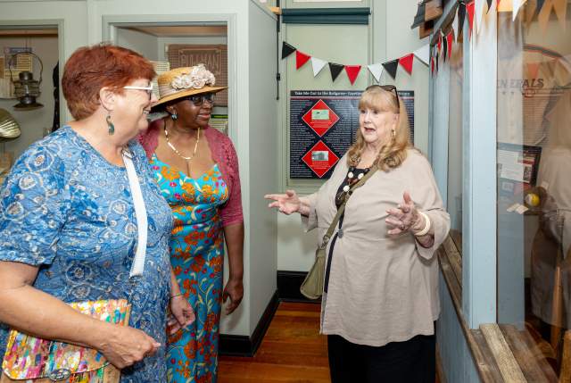 Three women chatting and laughing inside a local boutique, surrounded by colorful decor and display shelves.