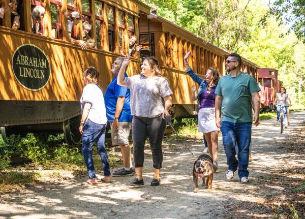 People enjoying a beautiful day walking alongside the steam engine on the heritage rail trail