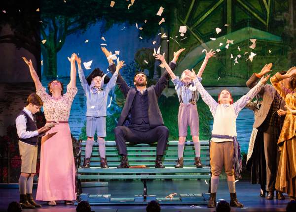 theatre stage with cast raising arms into air