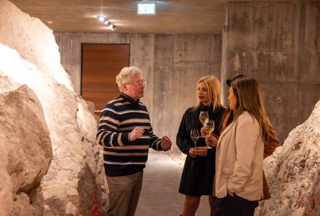 Group_Listening_to_a_Guide_While_Holding_Wine_Glasses_Inside_the_Wine_Caves