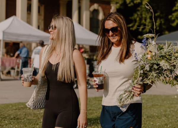 Friends carrying flowers and coffees at the Farmers Market