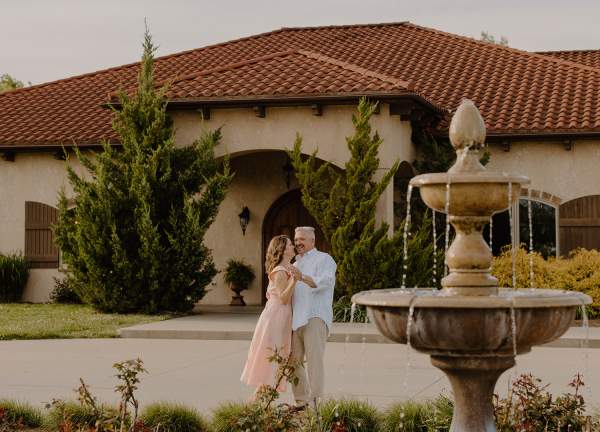 Couple dancing in front of Tuscan Hills Winery with fountain in foreground