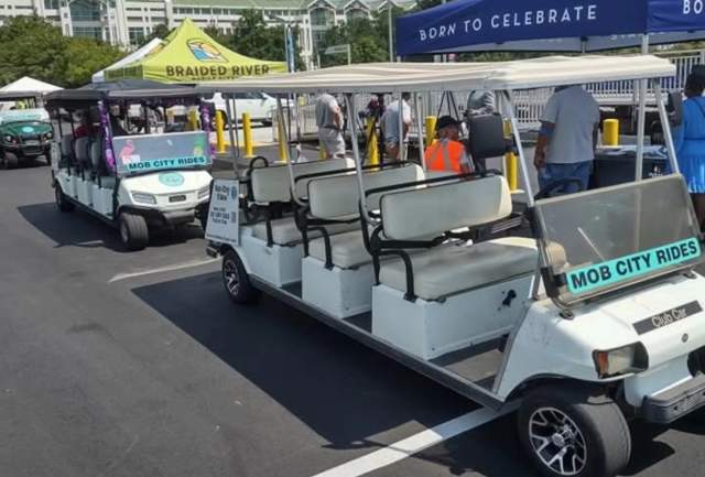 Two white eight-seater golf carts in front of a blue tent