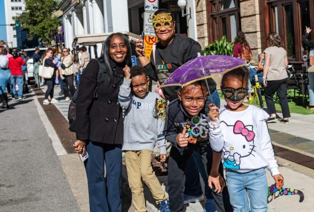 A family of five hold festive umbrellas on the street