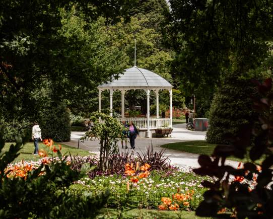 A couple walking the beautiful Queenstown Gardens loop with the verandah in the background